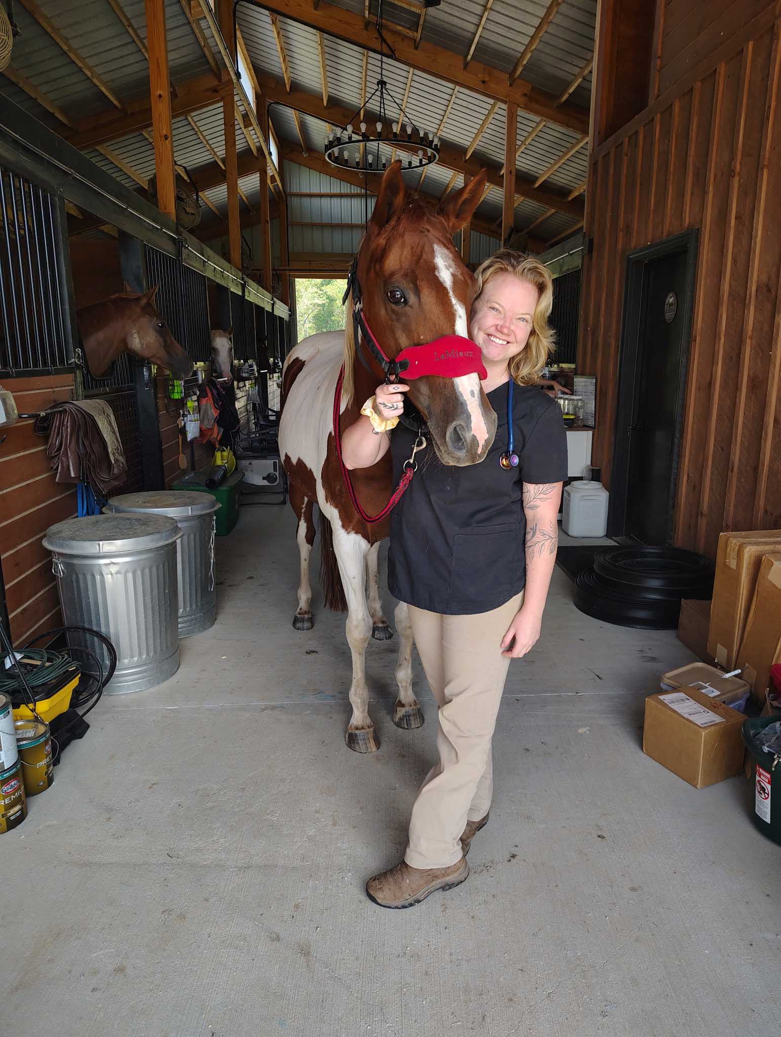 Woman, horse in stable.