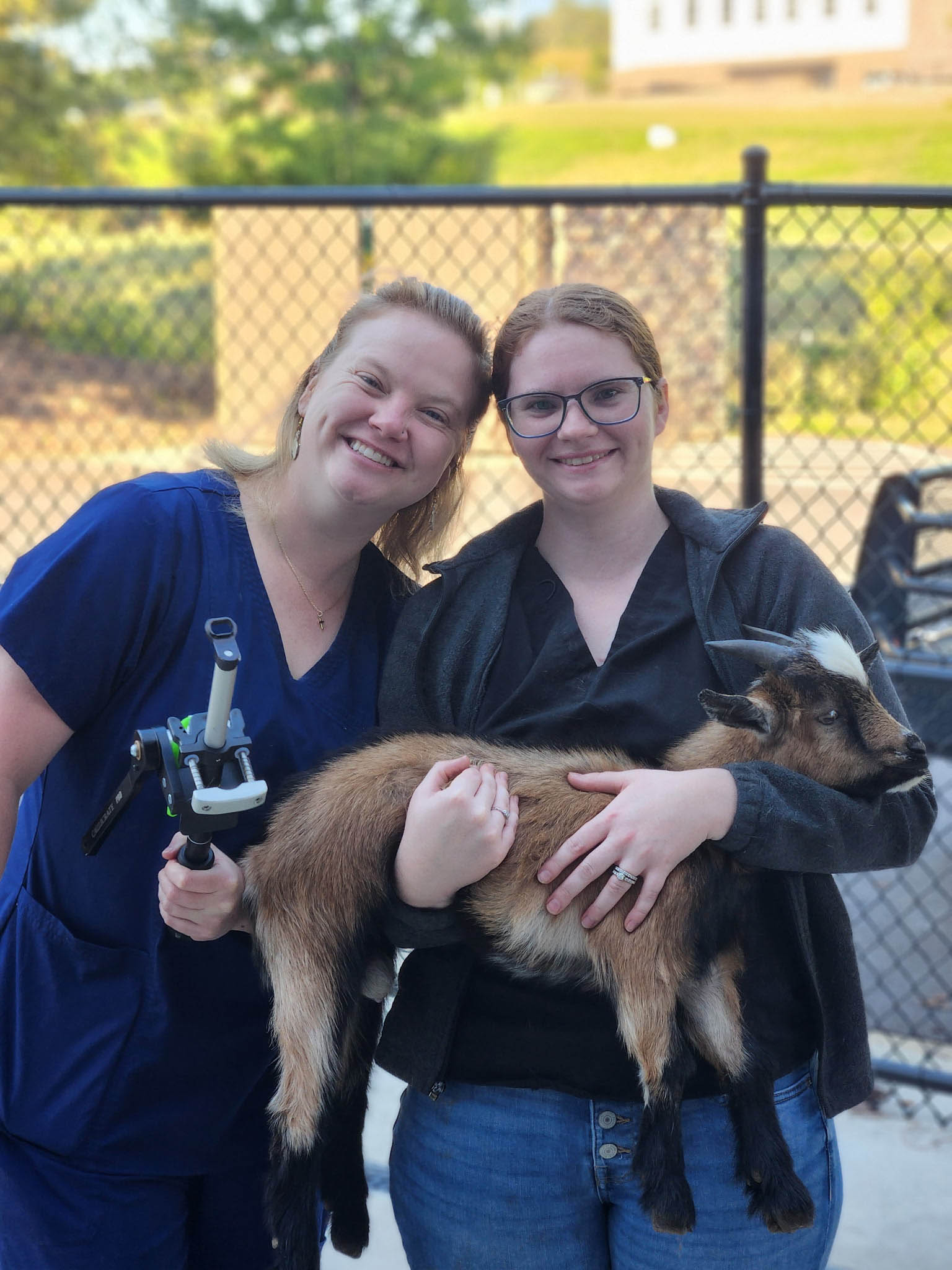 Women holding small goat